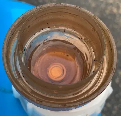 計量カップに入れた茶褐色の熟成木酢液